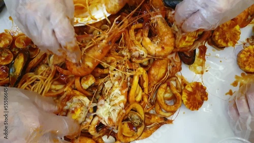 hand picking shrimp bucket cajun bbq poured on table top eating party seafood steamed sauce