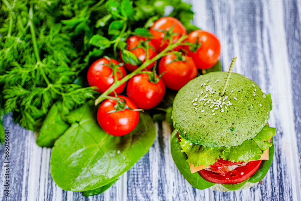 Closeup top view of vegan green burger with vegetables and tomato sauce on wooden table. Vegan food 