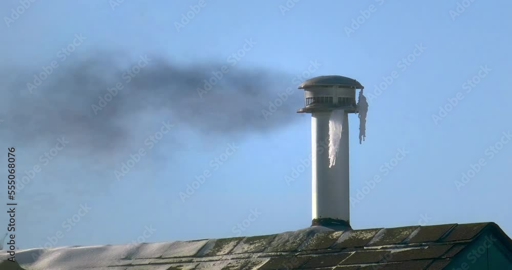 A metal chimney exhaust on asphalt roof with cap. Frozen chimney with ice during extreme cold weather in winter. Frozen solid icing up chimney, that could cause blockages due to icicles. A metal chimney exhaust on asphalt roof with cap. Frozen chimney with ice during extreme cold weather in winter. Frozen solid icing up chimney, that could cause blockages due to icicles.
