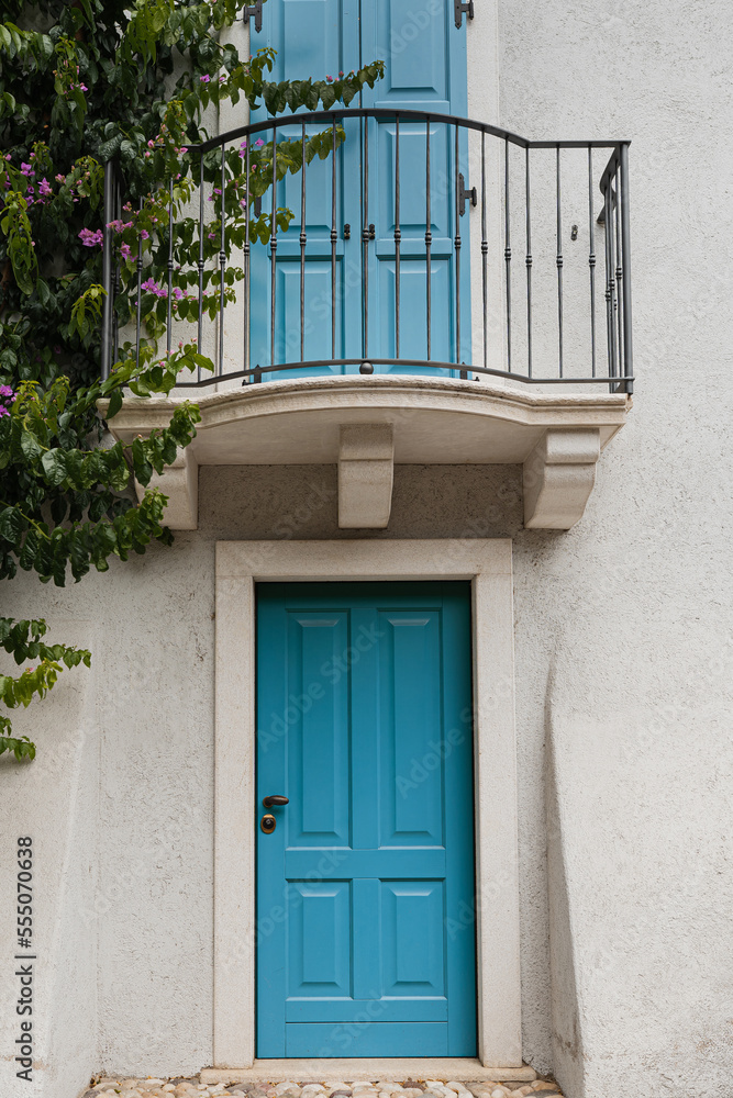 Old historic Italian architecture. Blue wooden door, balcony, blooming bush, pastel walls
