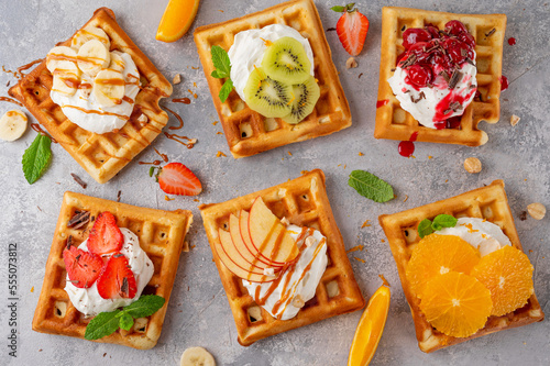 Homemade waffle with a cream, a variety of fruits, berries and sauces on a gray background. Traditional Belgian waffles. Top view.
