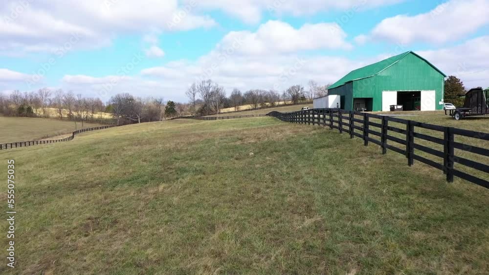 Aerial moving down a fence row on a horse farm in Kentucky with a large green barn on the right bluegrass state. Aerial moving down a fence row on a horse farm in Kentucky with a large green barn on the right bluegrass state.