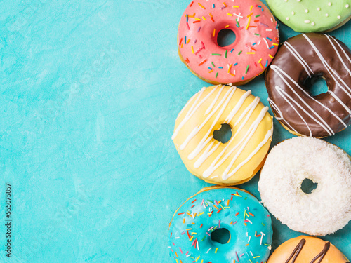 Top view of assorted donuts on blue concrete background with copy space. Colorful donuts background. Various glazed doughnuts with sprinkles.