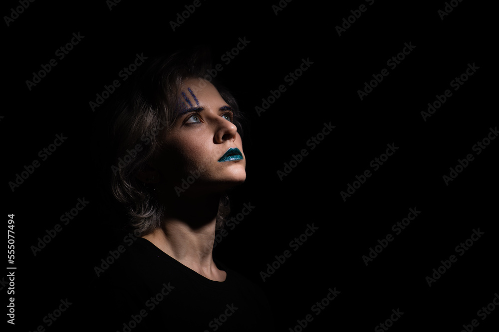dark dramatic female portrait with trendy teal color lipstic. blond hair woman looking up, mysterious portrait of woman on dark background