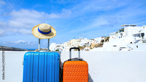 Fototapeta Naklejka Na Ścianę i Meble -  Summer concept with two luggage with hat and landscape view of Oia town in Santorini island in Greece , Greek landscape as blue sky background