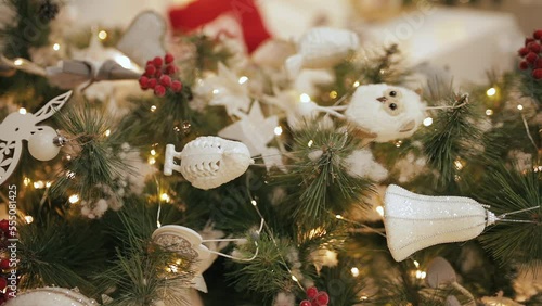 Christmas fir tree decorated with wooden, glass and soft toys and golden garland lights. Vertical close up shot