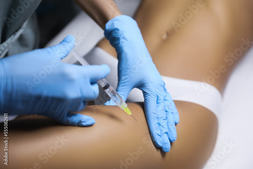 Young woman getting legs injection in salon  closeup