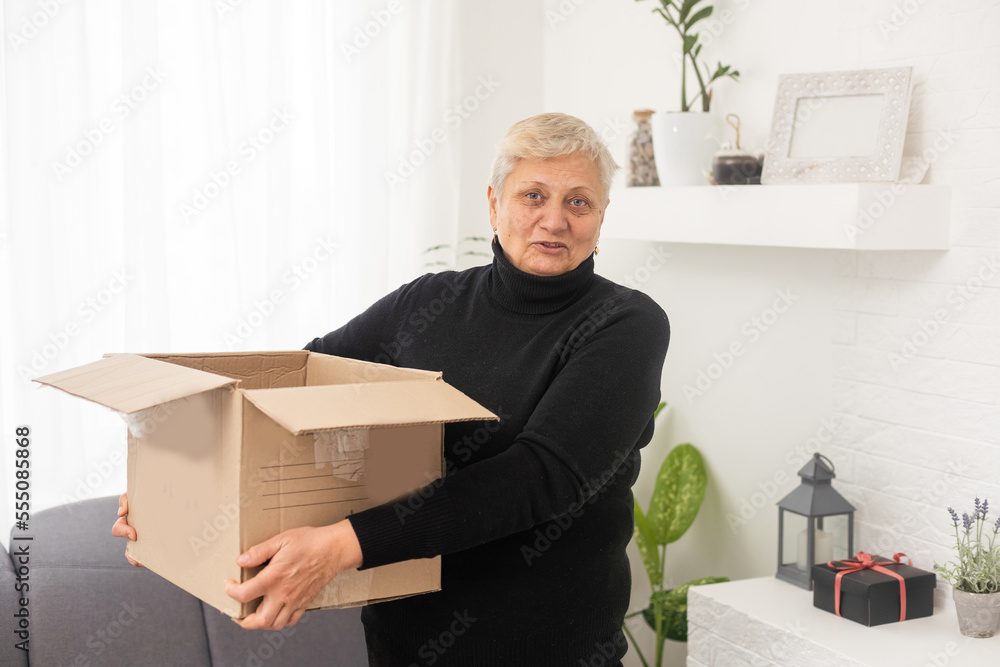 Elderly woman unpacking things in new house. Female hands opening cardboard box. Real estate, purchase, moving concept. Elderly woman unpacking things in new house. Female hands opening cardboard box. Real estate, purchase, moving concept.