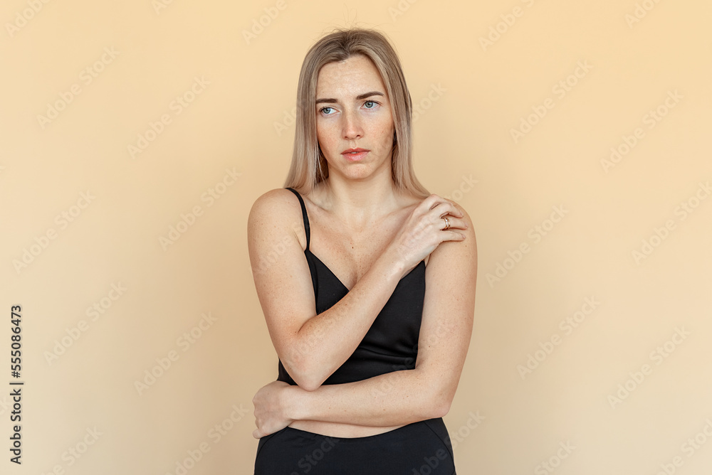 Portrait of the thoughtful upset woman standing over beige background, lost in thoughts. Pensive unhappy girl feeling lonely and depressed, thinking about relationship or personal problems Portrait of the thoughtful upset woman standing over beige background, lost in thoughts. Pensive unhappy girl feeling lonely and depressed, thinking about relationship or personal problems