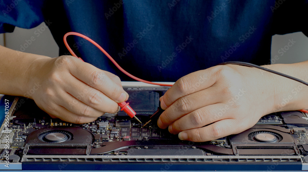 A technician is using his hand to measure a faulty electronic component on the motherboard board. A technician is using his hand to measure a faulty electronic component on the motherboard board.