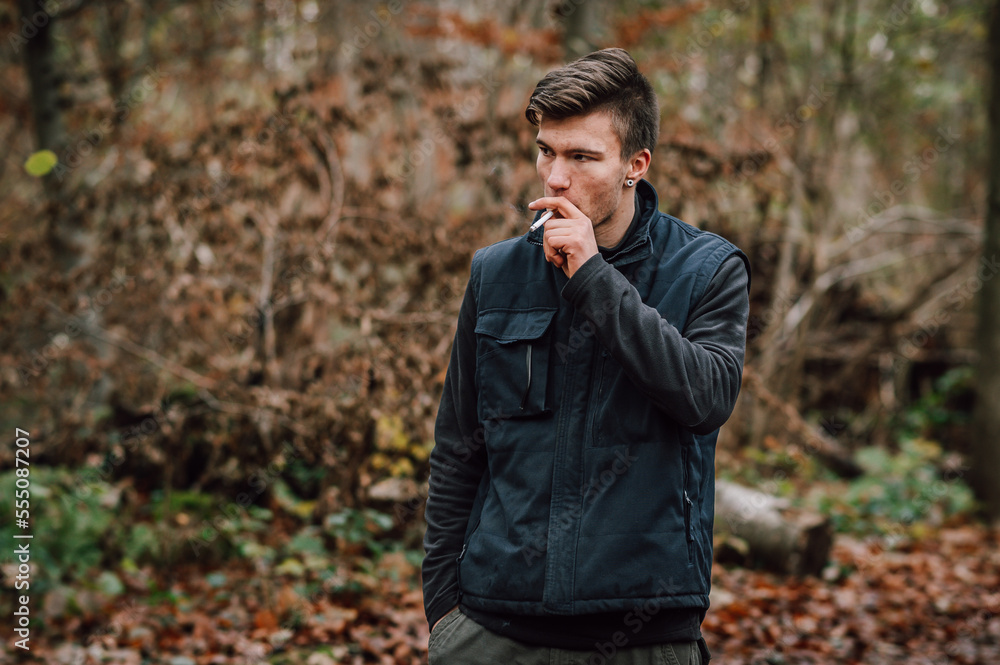 Mann zieht an einer Zigarette. Blick zur Seite. Im Wald, in der Natur. Mann zieht an einer Zigarette. Blick zur Seite. Im Wald, in der Natur.