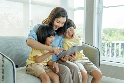 Happy Asian family male and female parents Teaching or helping with their children's homework. On holiday. Staying at home happily.