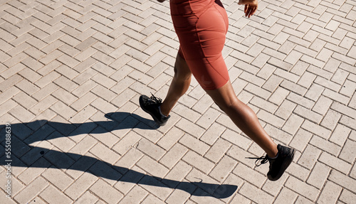 Fitness, feet and black woman running workout lifestyle for wellness, cardio and strong legs. Training, exercise and marathon preparation of athlete girl on sidewalk in sunshine for wellbeing.