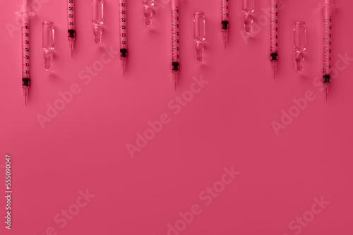 Syringes and ampoules toned in trendy magenta color of year 2023 in flat lay style. Cosmetology and medicine background. Virus vaccine concept.