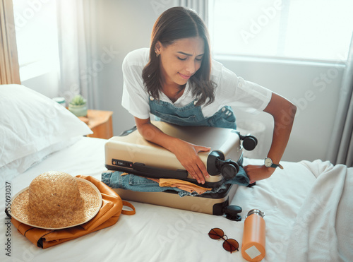 Woman, overloaded suitcase and luggage bag in bedroom for travel, vacation and international journey, holiday and trip. Female tourist struggle to close baggage full of clothing, packing and problem photo