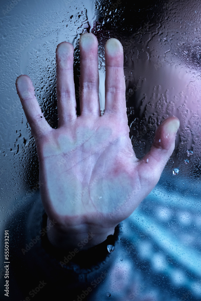 Protect children and young underage people from violence, exploitation, abuse, and neglect concept. Young girl screams and making STOP gesture behind wet glass. Vertical image.