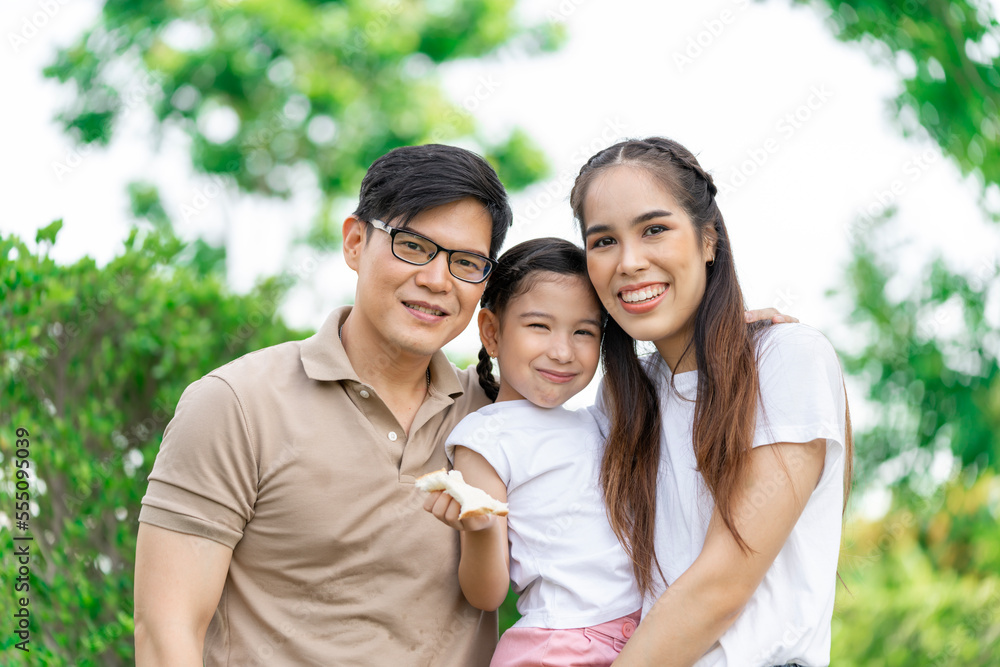 Young Asian parents doing activities eating and playing with their daughter in the front yard during the holidays happily. Young Asian parents doing activities eating and playing with their daughter in the front yard during the holidays happily.