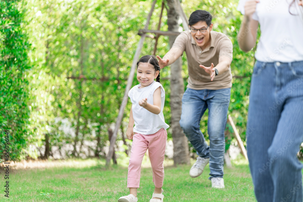 Young Asian parents doing activities eating and playing with their daughter in the front yard during the holidays happily.