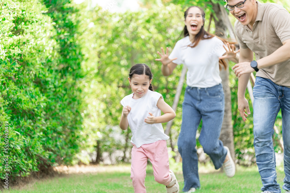 Young Asian parents doing activities eating and playing with their daughter in the front yard during the holidays happily. Young Asian parents doing activities eating and playing with their daughter in the front yard during the holidays happily.