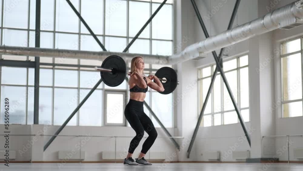 Strong, beautiful girl in her 30s sweating in a gym while building her