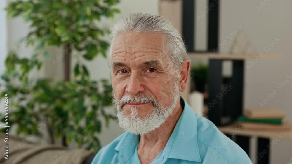 Portrait of the senior caucasian man sitting on the sofa at home and looking at camera. Happy elderly senior posing for close up view in living room. Leisure time, people concept Portrait of the senior caucasian man sitting on the sofa at home and looking at camera. Happy elderly senior posing for close up view in living room. Leisure time, people concept