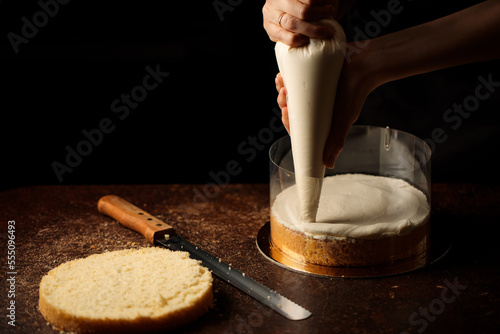 the process of assembling a biscuit cake in an acetate film, applying a layer of cream from a pastry bag