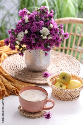 Cup of aromatic coffee and beautiful flowers on white table