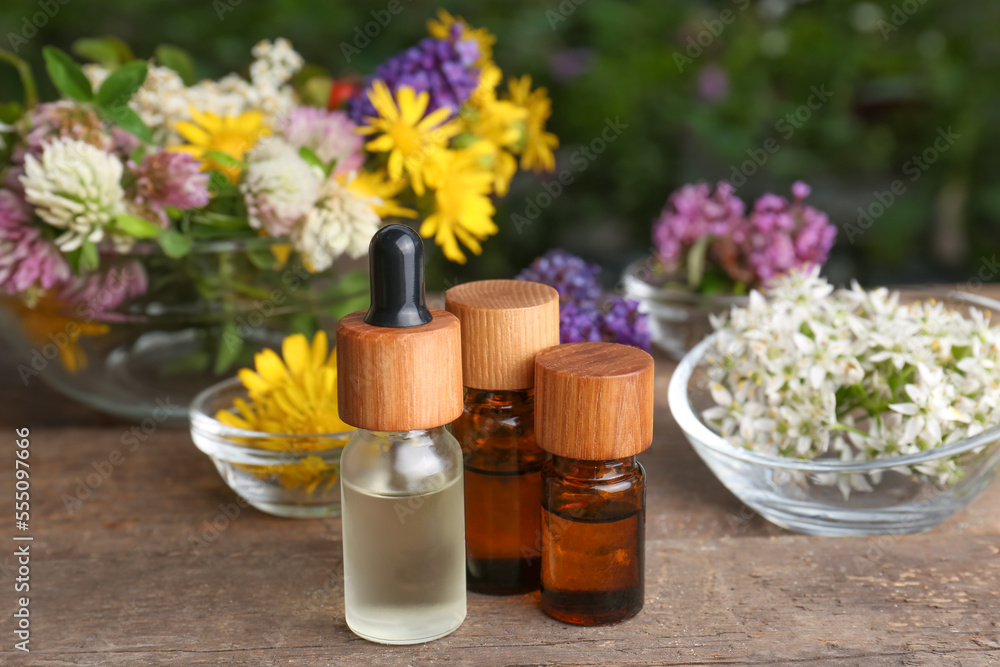 Bottles of essential oils and many beautiful flowers on wooden table Bottles of essential oils and many beautiful flowers on wooden table