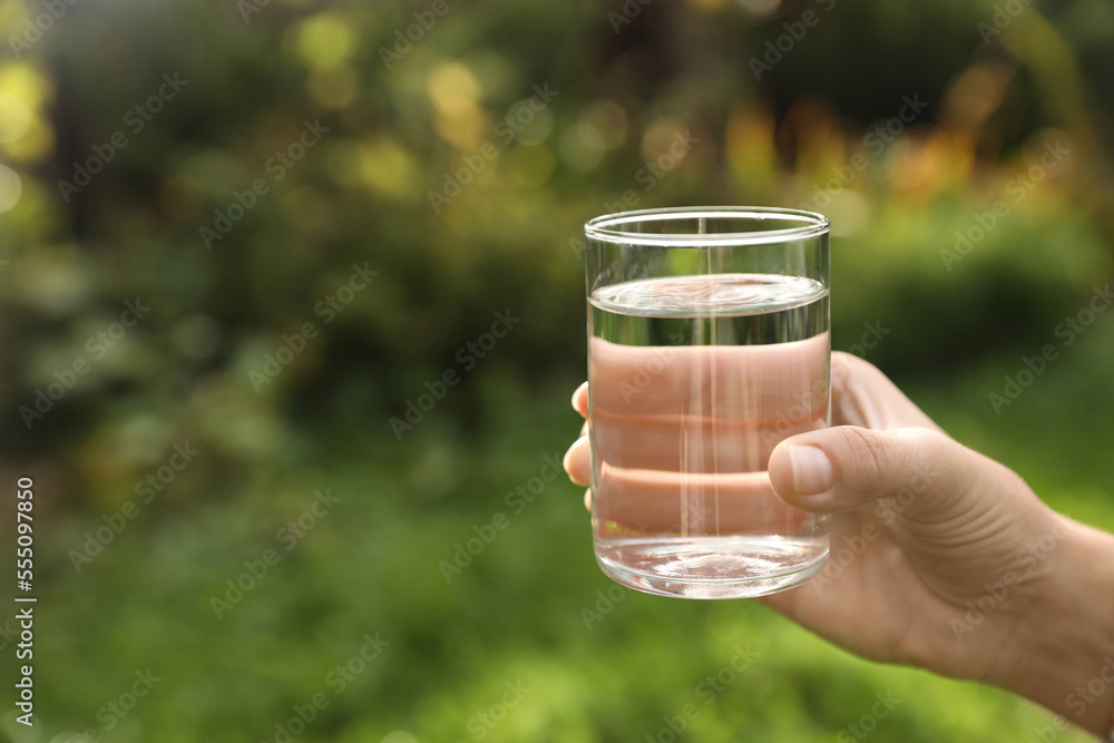 Woman holding glass of fresh water outdoors, closeup. Space for text Woman holding glass of fresh water outdoors, closeup. Space for text