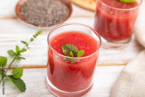 Watermelon juice with chia seeds and mint in glass on a white wooden background with linen textile. Side view, selective focus.