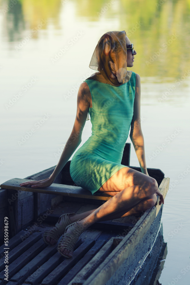 Young elegant woman wearing dress and scarf sitting in the fishing