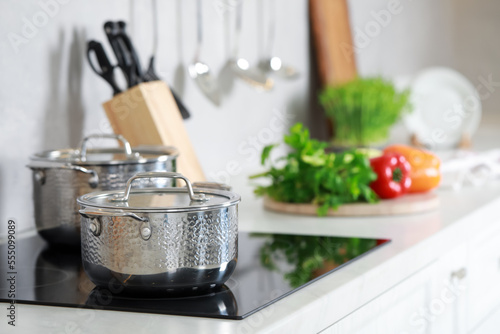 Pots with lids on cooktop in kitchen, space for text. Cooking utensils