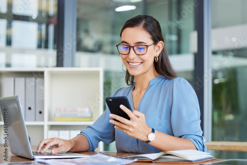 Business woman, laptop and smile for phone, communication or reading at the office. Happy female employee event planner checking email, social media or post on smartphone and computer at workplace
