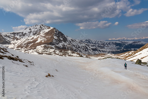 Woman with backpack walking on snow covered hiking trail with panoramic view on snowcapped mountain peak Kreiskogel, Seetal Alps, Styria (Steiermark), Austria, Europe. Remote nature in mur valley