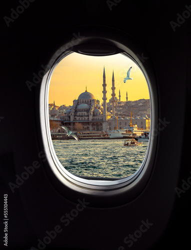 Istanbul sunset in old city with mosque, minarets and passenger ships, view from a porthole window of airplane. Concept for travel agency, airline company or passenger transportation in Turkey.