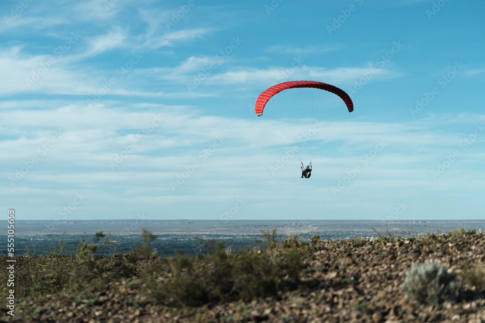 Red paragliding take offs on beautiful blue sky with clouds Red paragliding take offs on beautiful blue sky with clouds