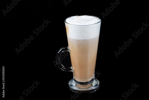 Latte macchiato in beautiful cup on wooden background with natural shadow. Cappuccino frothy coffee and milk drink in clear glass cup. Chai Latte pouring shot. Chai Latte Drink.