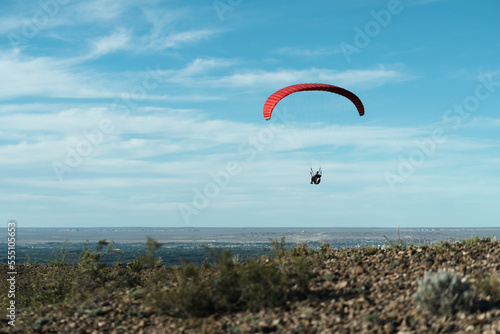 Red paragliding take offs on beautiful blue sky with clouds