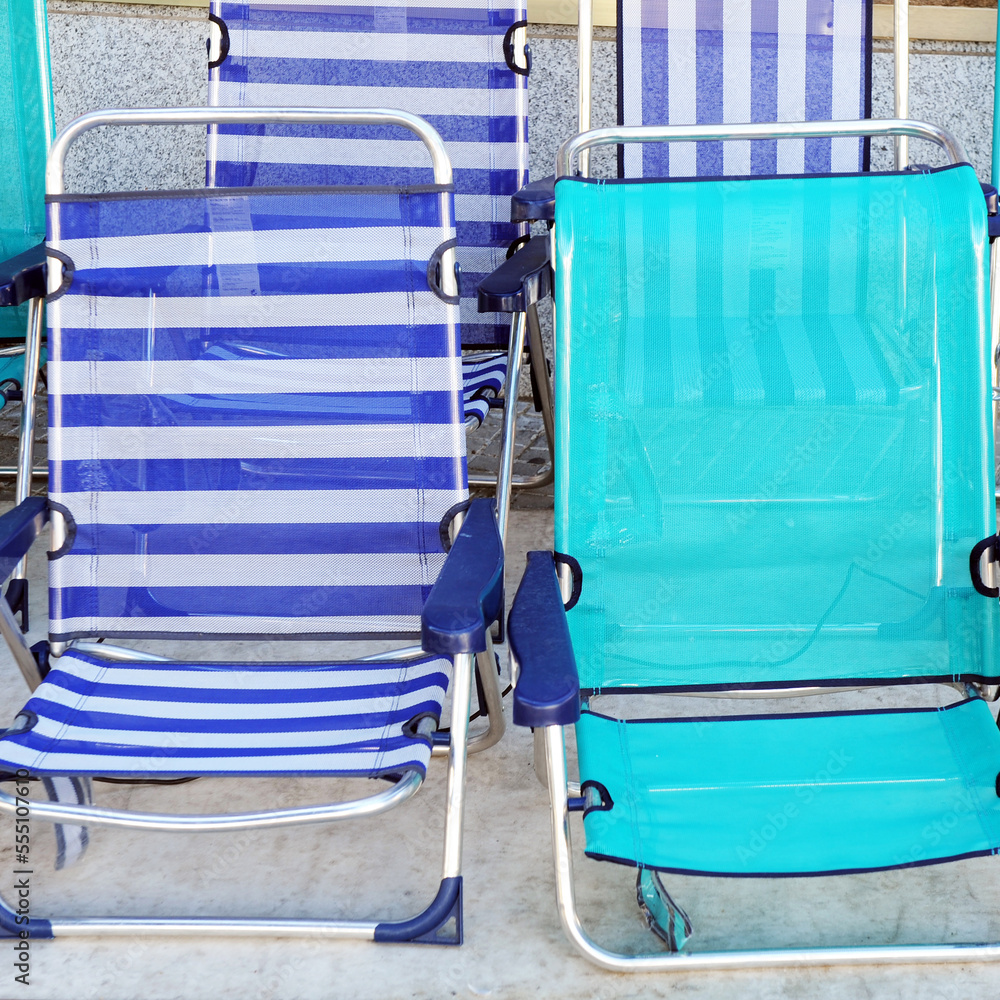 Aluminum and blue plastic chairs. Beach chairs to sit and sunbathe on the seashore. Sale of chairs for the beach.
