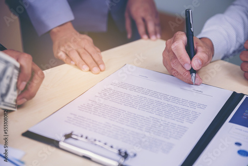 Businessman puts signature on contract at business meeting after negotiations with business partners. Selected focus