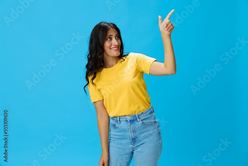Woman in yellow t-shirt on blue background posing gestures emotions and signals with smile  hands up happiness copy space