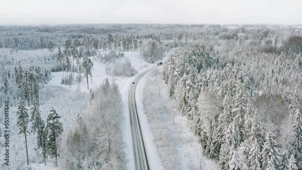 Flying over snowy road that cuts through a winter landscape Flying over snowy road that cuts through a winter landscape