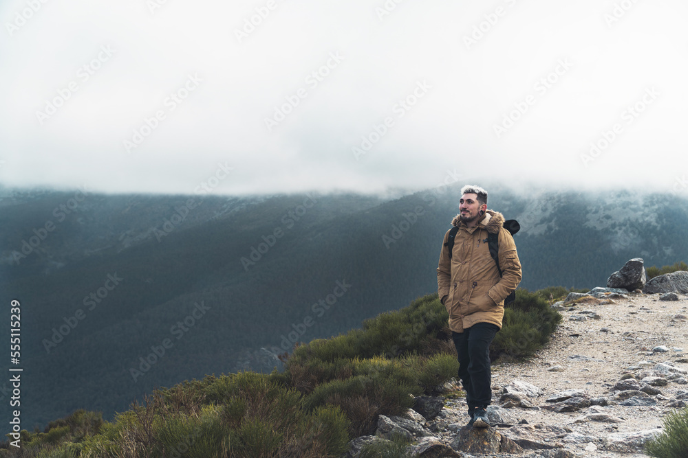 Boy walking up the mountain on a cloudy day with the mountains in the background Boy walking up the mountain on a cloudy day with the mountains in the background