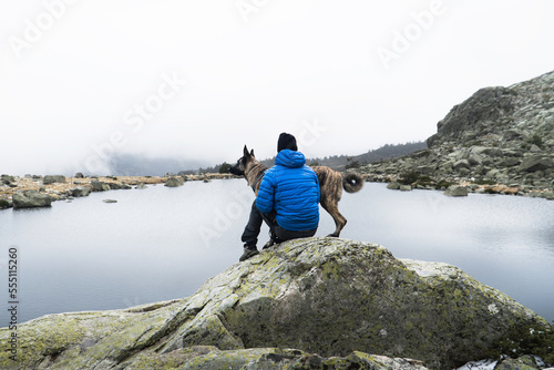 Dog and his owner in a lake on a rock a cloudy day