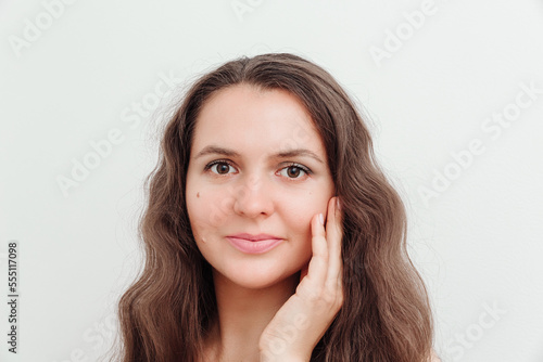 Portrait of beautiful brown hair young woman, touching her face. Scin care, natural beauty, perfect skin,cosmetics and wellness concept. Studio shot, white background.