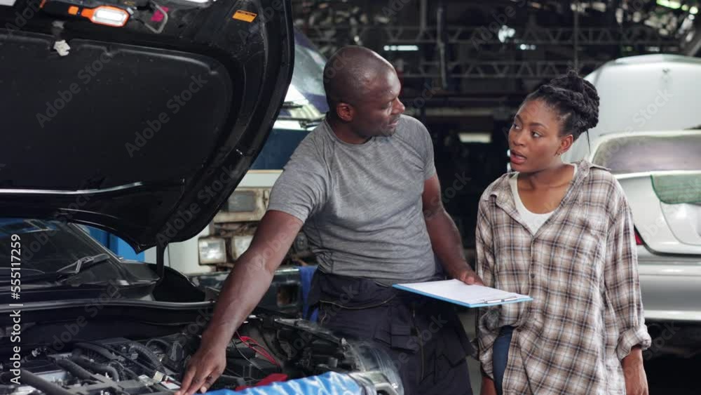 Mechanic man worker repair car engine. African young female customer talking with owner and mechanic engineer worker at car repair service and auto store shop. Mechanic man worker repair car engine. African young female customer talking with owner and mechanic engineer worker at car repair service and auto store shop.