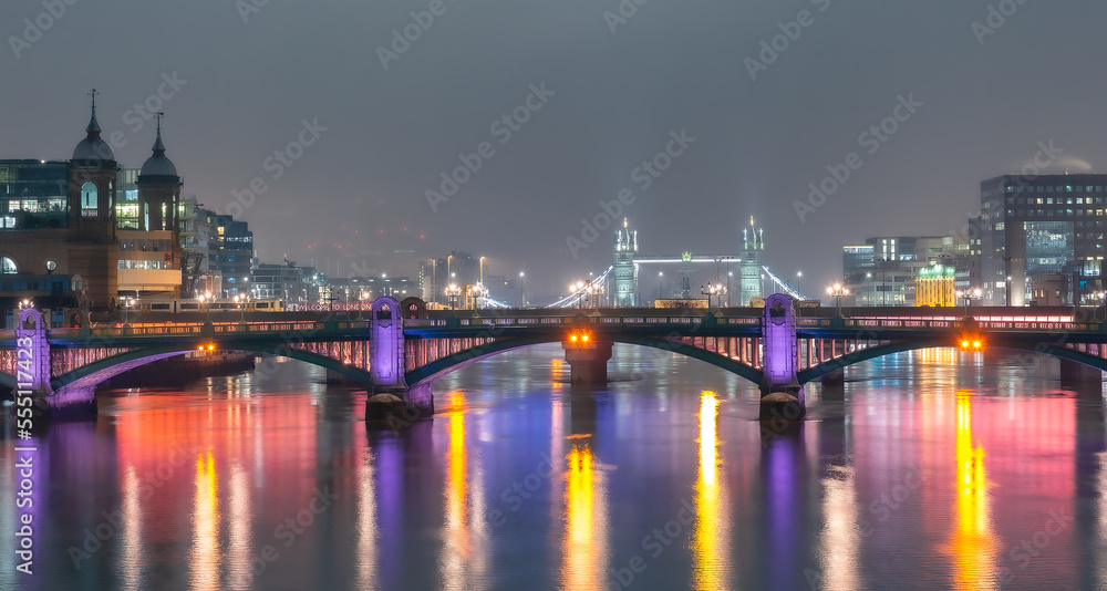 Panoramic view of the City of London and the London Bridge over the river Thames, illuminated at night