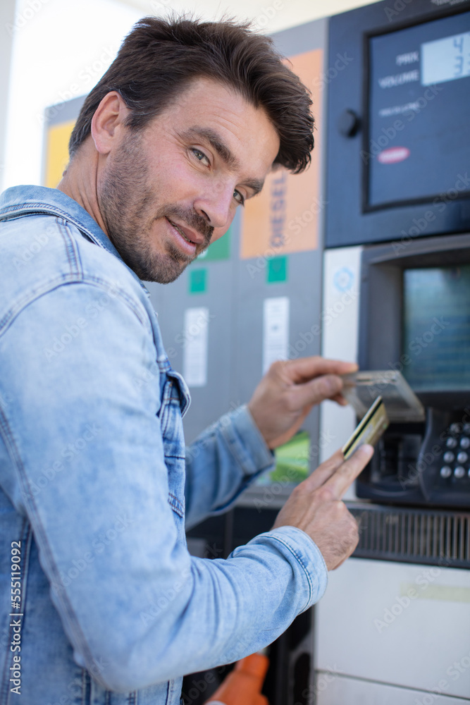 happy man holding credit card and smiling at gas station