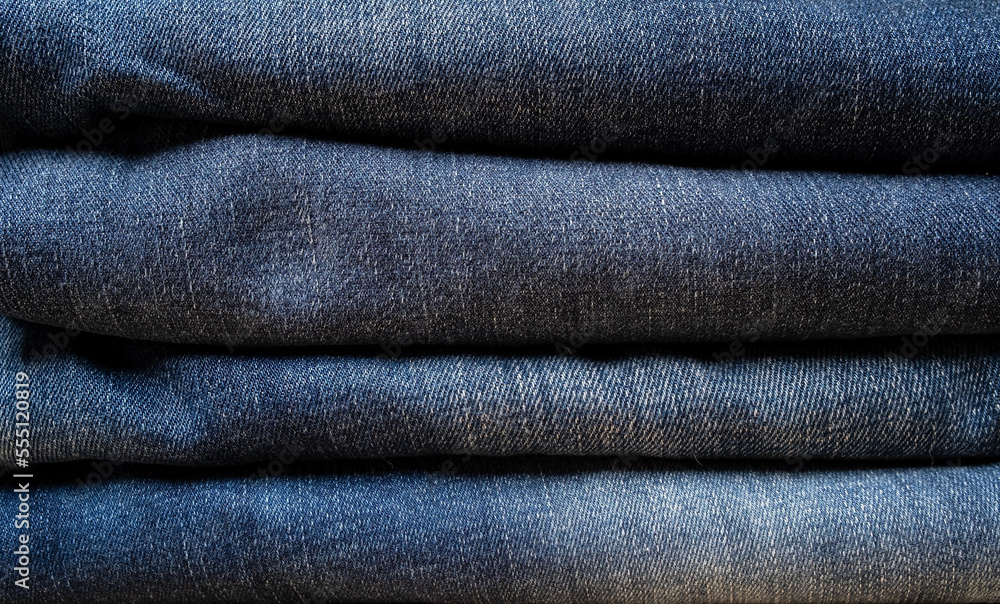 Jeans folded into a pile. Textured background. Copy space. Concept of the trading industry, sales. Jeans folded into a pile. Textured background. Copy space. Concept of the trading industry, sales.