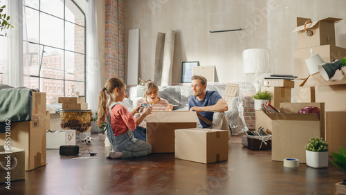 Foto Happy Homeowners Moving In: Lovely Couple Sitting on the Floor of Cozy Apartment Unpacking Cardboard Boxes, Little Daughter Joins them